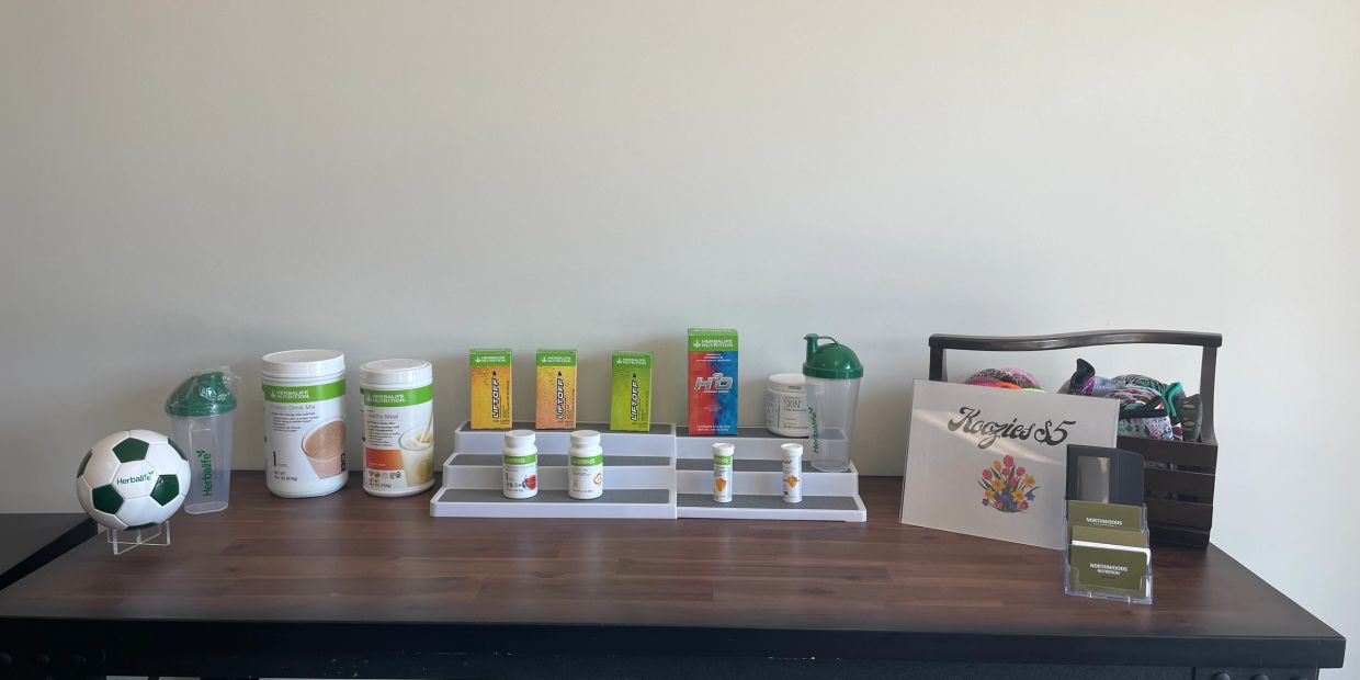 Table with Herbalife products, a soccer ball, and a basket of colorful socks.