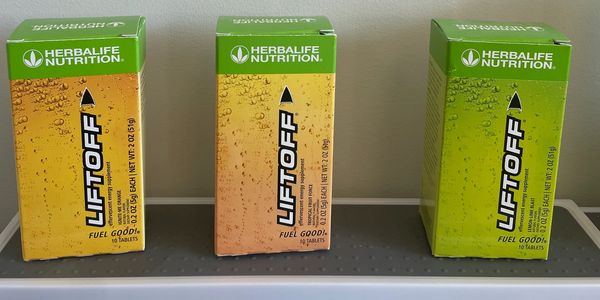 Three Herbalife Liftoff energy drink boxes on a shelf.