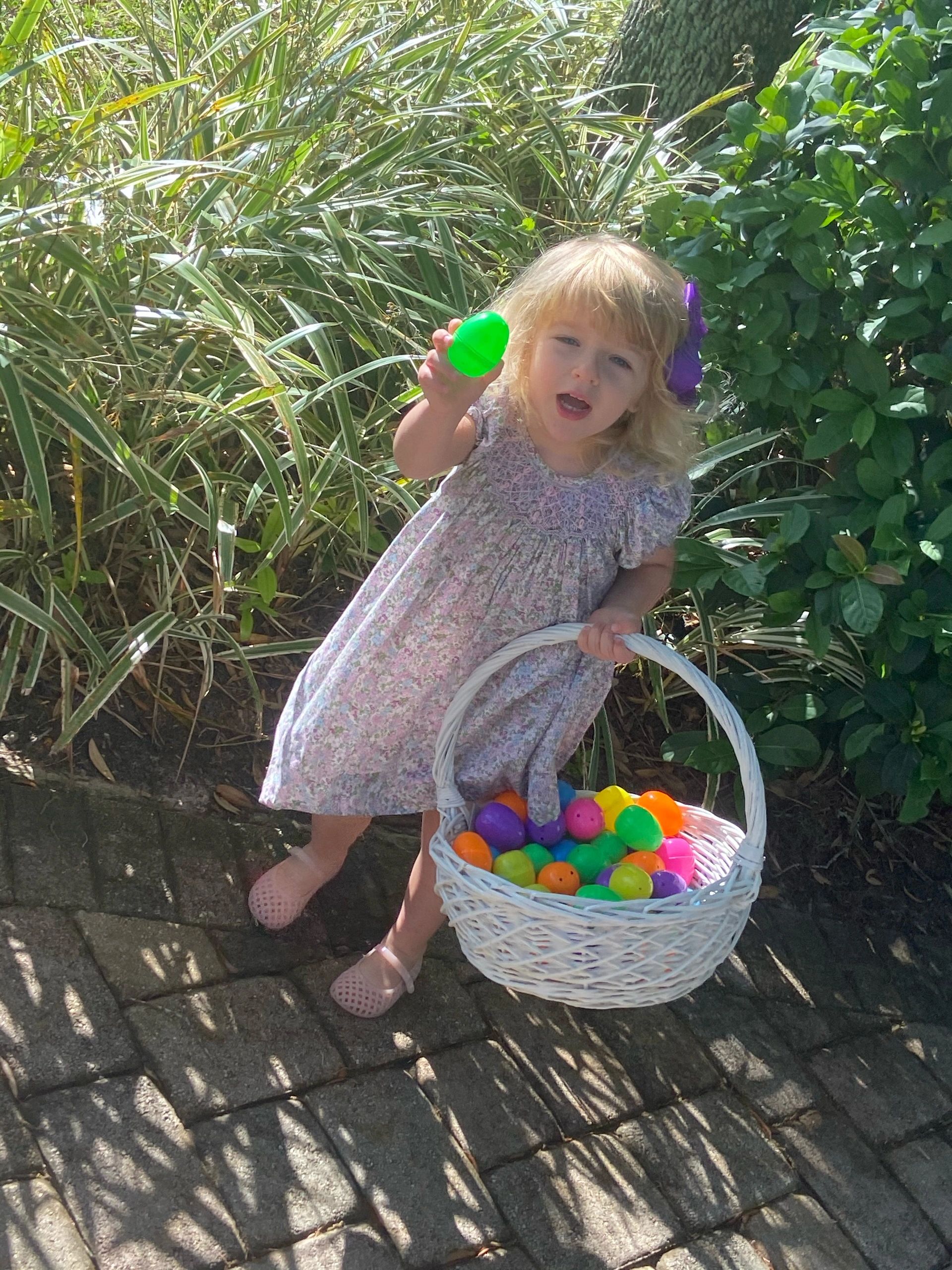 Happy girl holding Easter egg with basket of colorful eggs