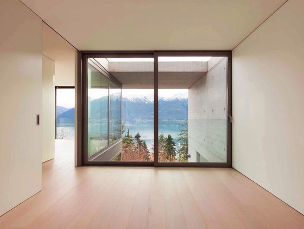 Minimalist room with large window showcasing mountain and lake views.