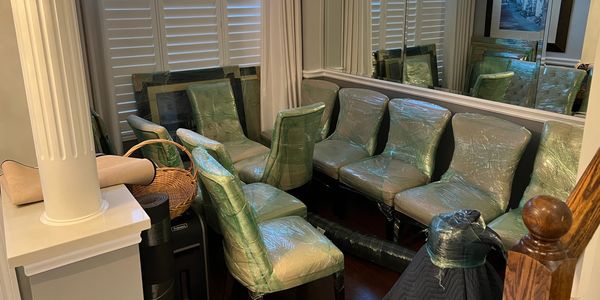 Dining chairs securely wrapped in shrink wrap, table protected with moving blankets.