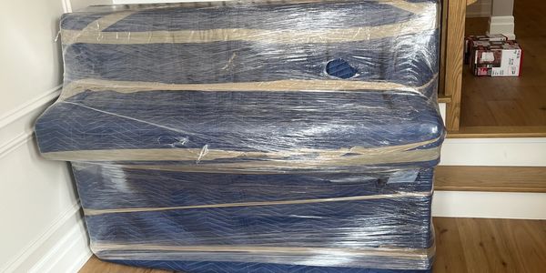 Upright piano carefully wrapped in blankets and shrink wrap for safe transport.