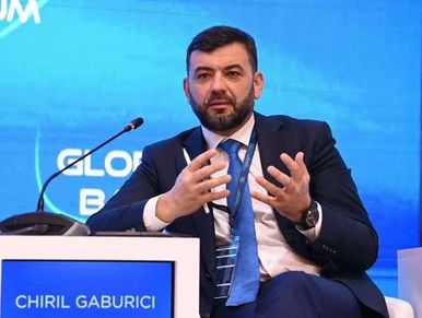 Man speaking at a conference with a sign showing "Chiril Gaburici."