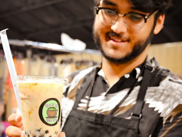 A man smiling while holding a cup of bubble tea from Magical Brews.