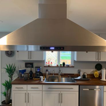 Modern kitchen with stainless steel hood and wooden countertop.