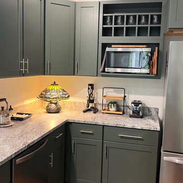 Modern kitchen corner with green cabinets and appliances.