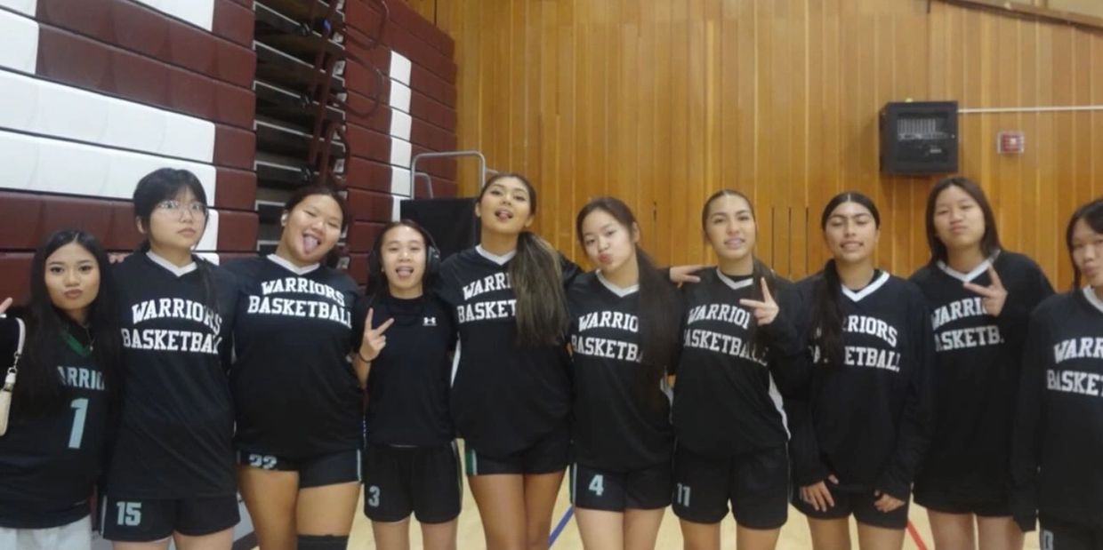 High school girls basketball team posing in gym.