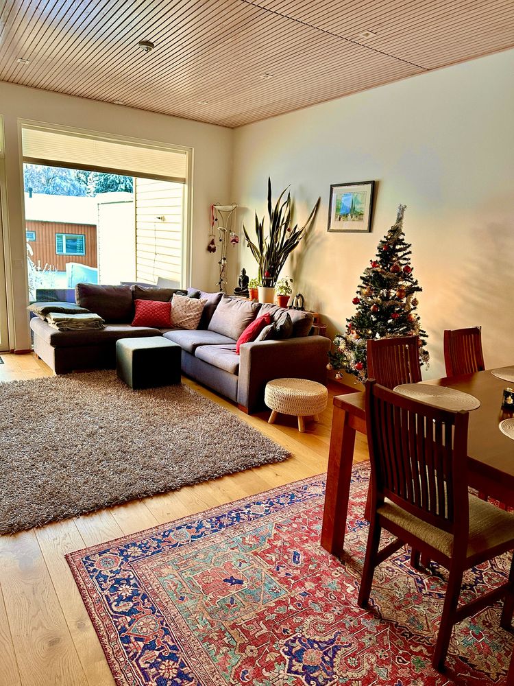 Cozy living room with sectional sofa, Christmas tree, and dining area.