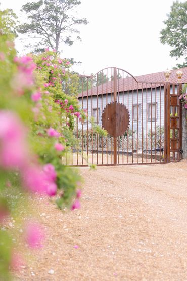 Rustic metal gate with a circular saw blade design at a countryside property.