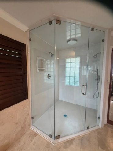 Modern glass-enclosed corner shower with dual showerheads and tiled floor.