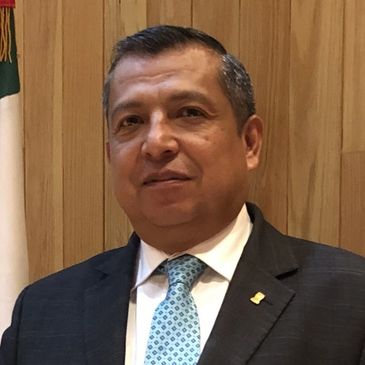 Hombre de traje posando frente a una pared de madera.