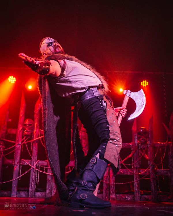 Performer in Viking attire striking a dramatic pose with an axe on stage.