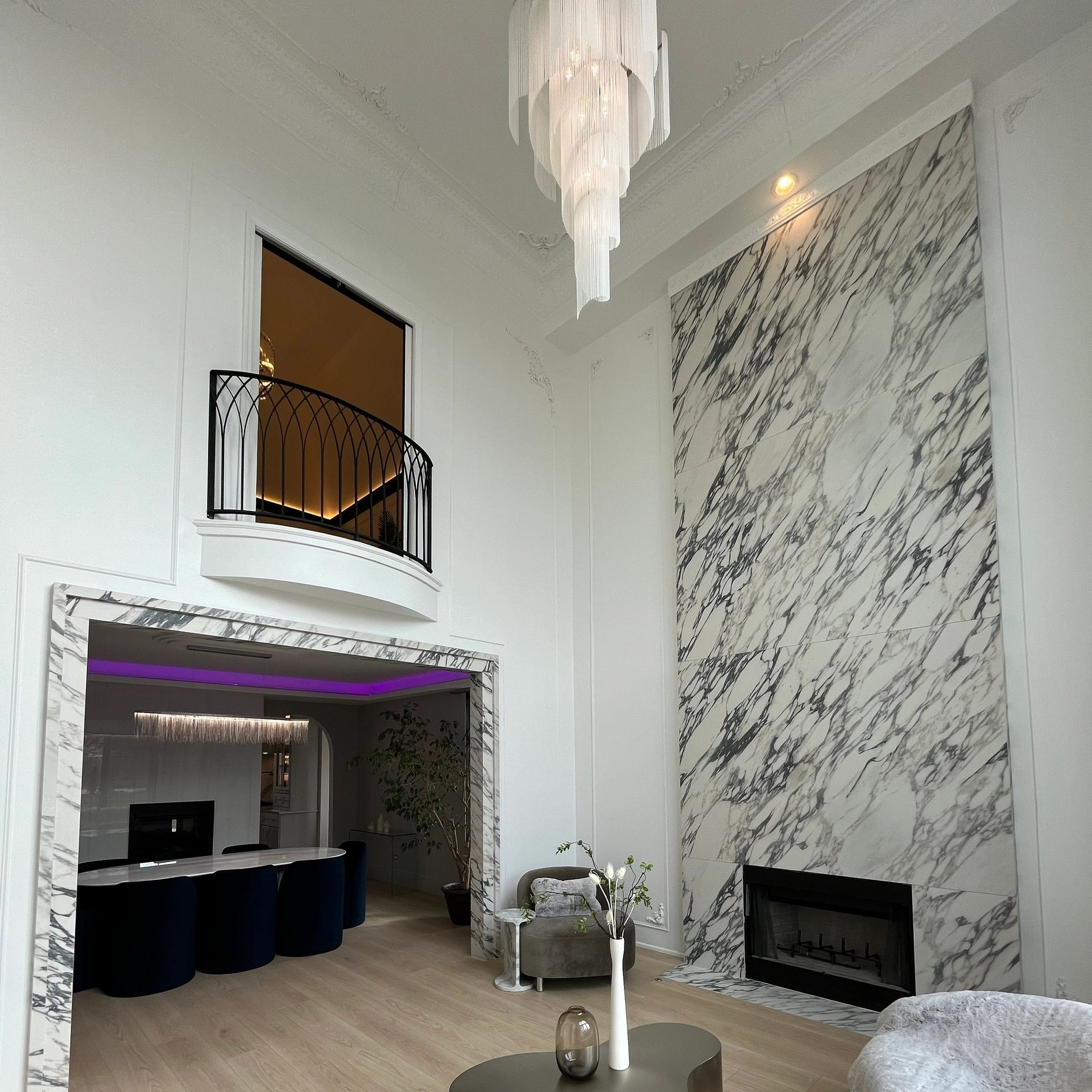 Modern living room with marble fireplace and elegant chandelier.