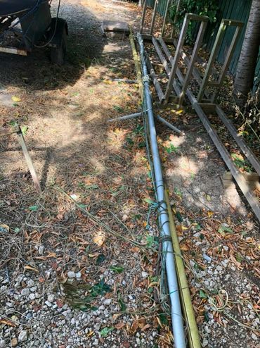 Metal poles and wire fencing laid on the ground outdoors.
