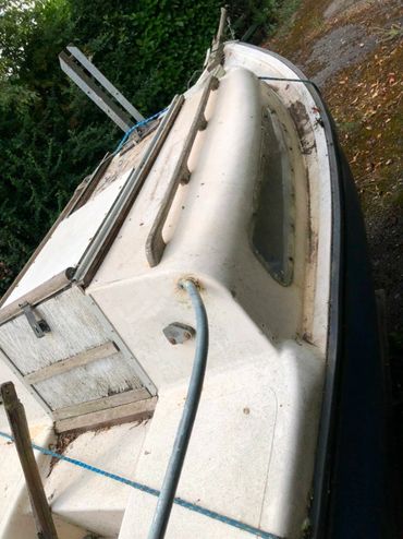 A small, weathered boat parked outdoors with visible ropes and a cabin.