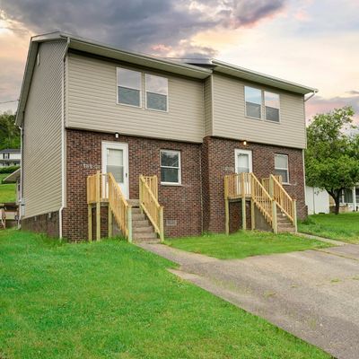 Two-story brick and siding duplex with front stairs and driveway.