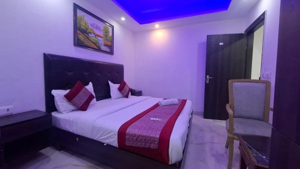 Modern hotel room with blue ceiling lighting and a neatly made bed.
