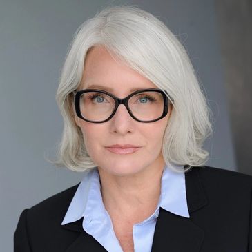 Professional middle-aged woman with white hair and glasses.