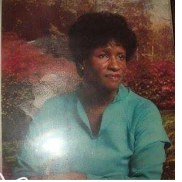 Portrait of Mrs. Robbie in a teal blouse against a warm, autumnal background.