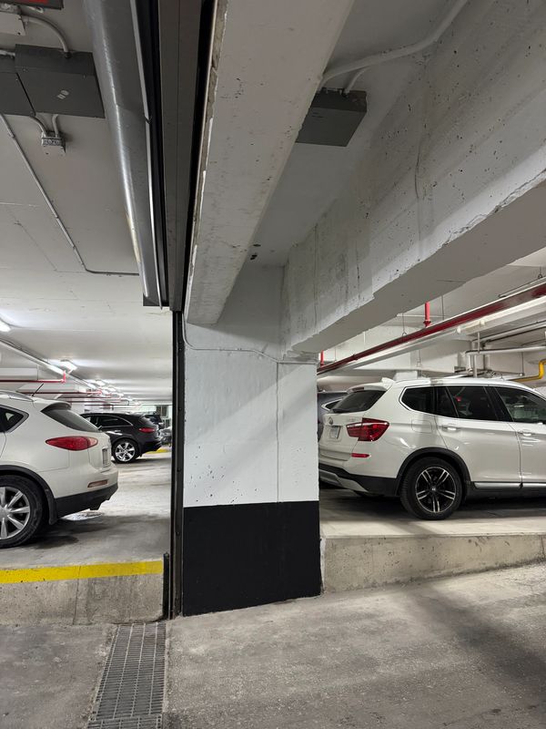 White SUVs parked in an indoor parking garage with concrete pillars.