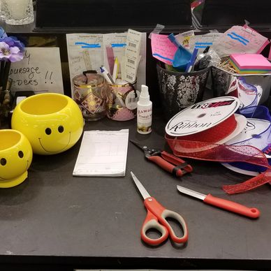 Crafting workspace with smiley pots, scissors, ribbons, and floral supplies.