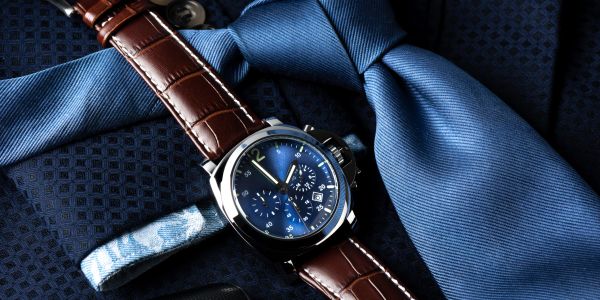 Luxury watch with brown leather strap and blue dial on a blue tie.