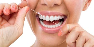 Close-up of a person flossing their teeth with a smile.