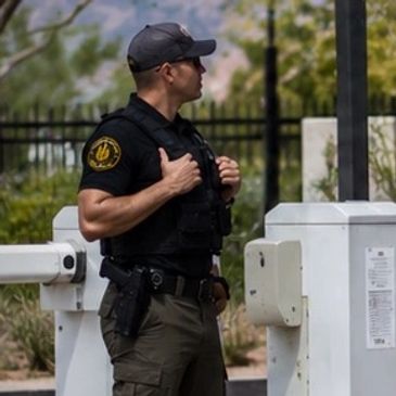 Uniformed security officer monitoring entrance gate.
