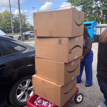 Four stacked Amazon boxes on a red wagon outdoors.