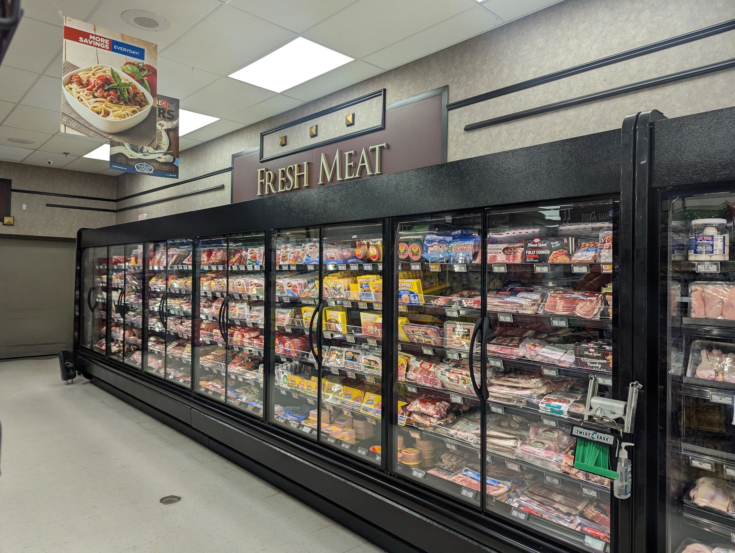 Grocery store aisle with fresh meat section and refrigerated display cases.