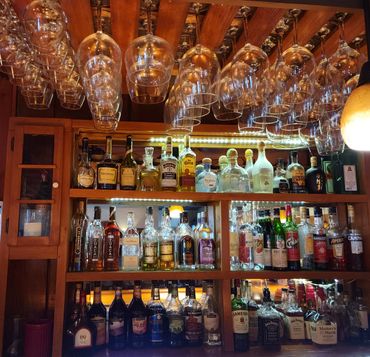 hanging wine glasses and self of alcohol bottles behind a bar