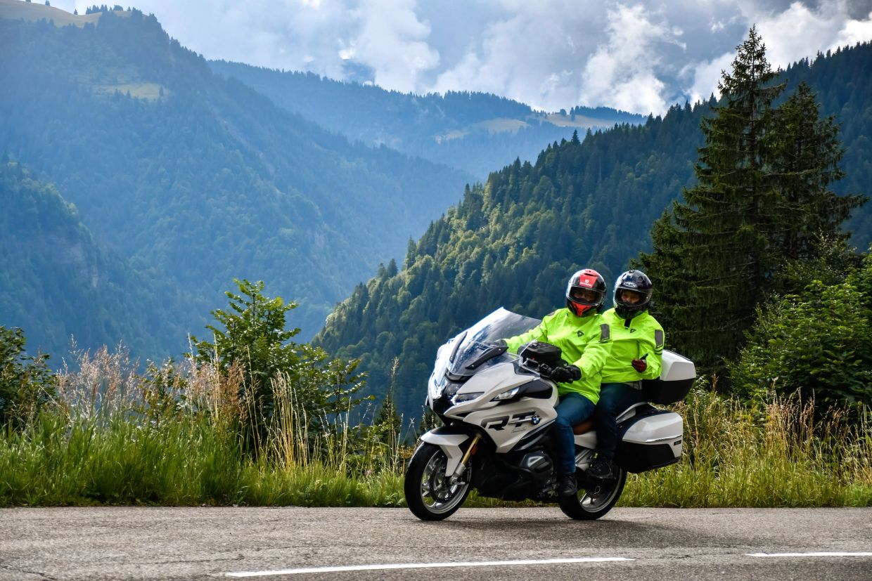 Two riders on a white motorcycle in mountainous scenery.