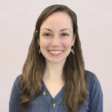Smiling woman with long brown hair wearing a blue top.