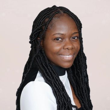 Smiling woman with long braided hair in a white and black outfit.