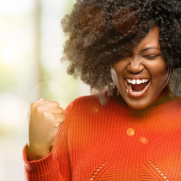 Excited woman in a red sweater celebrates with clenched fists and a joyful expression.
