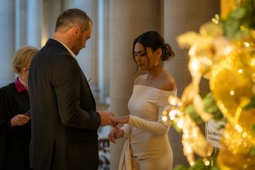 Groom places ring on bride at wedding ceremony at city hall