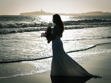 beautiful woman holding flowers overlooking the ocean at sunset