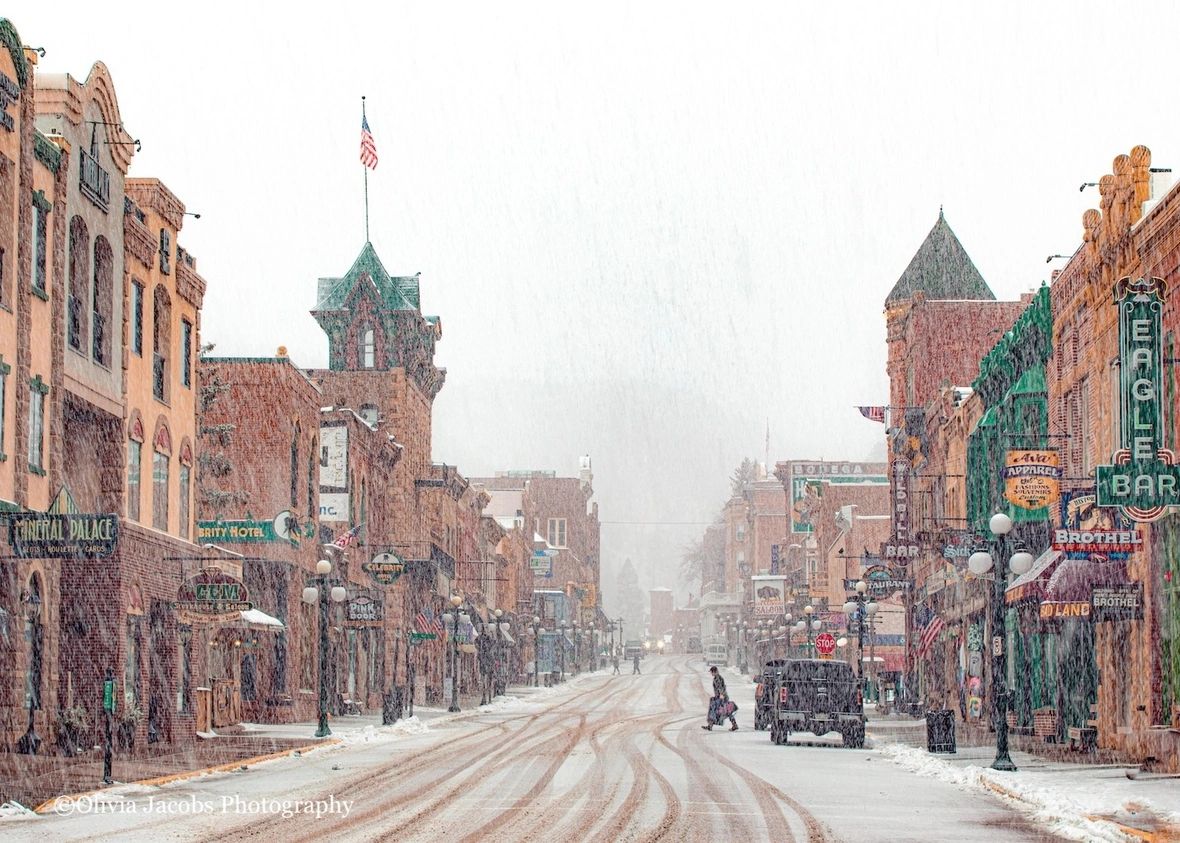 let it snow, photo by Olivia Jacobs of Deadwood Main Street in the snow and a man walking across the street with a suitcase