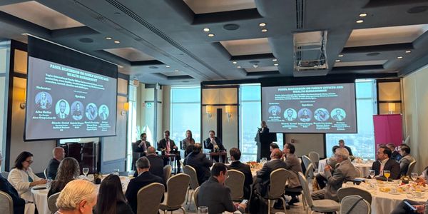 Panel discussion on family offices and wealth management in a conference room with attendees.