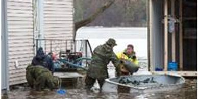 a photo where few people are rescuing someone on a bot where there is water all around