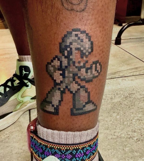 Pixelated video game character tattoo on leg.