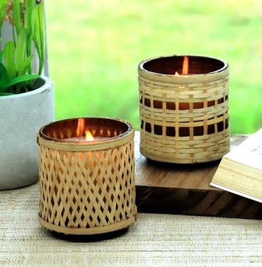 Two lit candles in woven bamboo holders on a table.