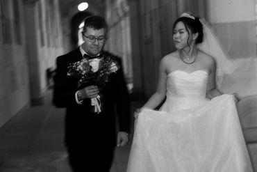 Black and white photo of a bride and groom walking together in a corridor.