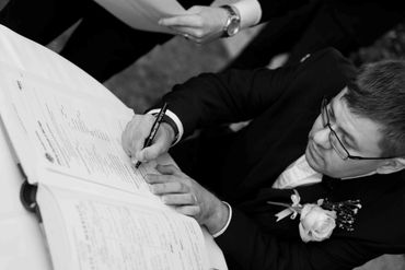 Man in suit signing a document at a formal event.