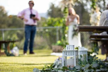 Decorative lanterns and greenery at an outdoor wedding ceremony.
