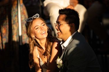 A happy couple smiling warmly at each other in soft sunlight.