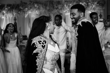 A joyful couple in ornate capes share a moment at a celebration.