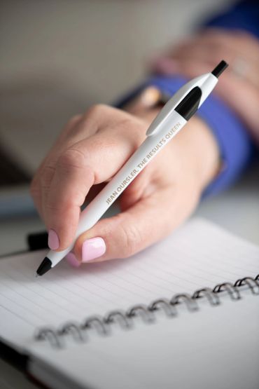 Person holding a pen with motivational text, ready to write in a spiral notebook.