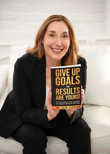 Woman smiling while holding a motivational book by Dr. Jean Oursler.
