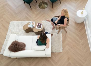 Two women having a conversation in a modern, cozy living room.